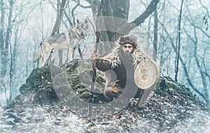 Shamanic man playing on shaman frame drum in the nature.