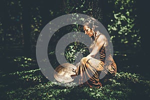 shamanic woman playing on shaman frame drum in the nature.