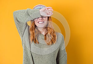 Shame. Close up young woman covering face with hands, isolated on yellow background. Ashamed girl