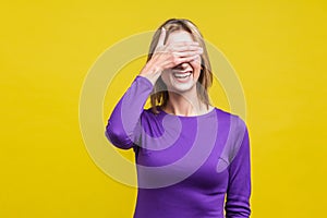 So shameful, i`d rather not watch this! Portrait of bashful positive woman covering eyes with hand.  on yellow background