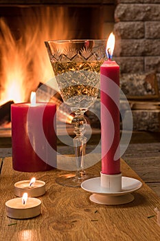 Shampagne glass, christmas candles against cozy firepace