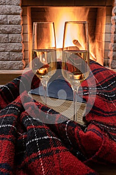 Shampagne glasses, opened book and wool scarf against cozy firepace photo