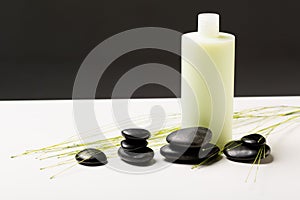 Shampoo bottle, massage stones and green plant