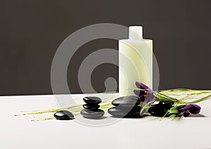 Shampoo bottle, massage stones and iris flower