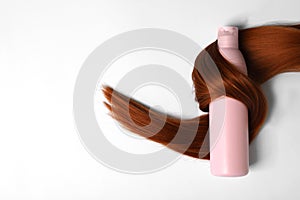 Shampoo bottle wrapped in lock of hair isolated on white. Natural cosmetic products