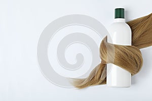 Shampoo bottle wrapped in lock of hair isolated on white. Natural cosmetic products