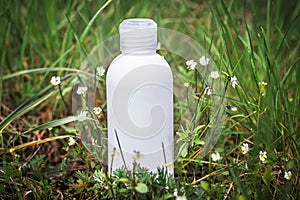 Shampoo with field pansy tincture. Cosmetic bottle, shampoo dispenser product package. Plastic bottle mockup in a meadow