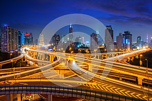 Shanghai elevated road junction and interchange overpass with office buliding skyscrapers downtown district at night in Shanghai,