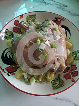 Shank of pork over a potatoes salad