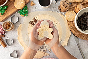 Shape of gingerbread man from dough in female hands in the kitchen.