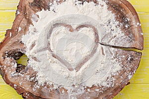 Shape of heart drawn on white flour.