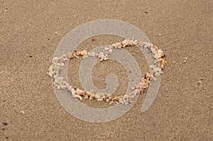 The shape of heart made from small shells on the sand beach, selective focus