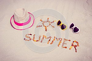 Shape of sun and word summer, sunglasses and straw hat on sand at beach, sun protection, summer time