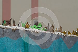 Shards of broken glass bottles are concreted on top of the wall to scare away those who want to enter the area illegally