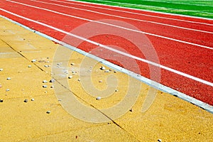 Shards and parts of hardened concrete or bricks are scattered on the running track of a sports stadium with green