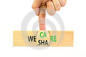 We share and care symbol. Concept word we share we care on wooden block. Businessman hand. Beautiful white table white background