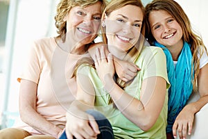 They share the same smile. A beautiful mature woman being hugged by her mother and daughter.