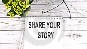 SHARE YOUR STORY text concept write on notebook on wooden background