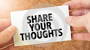 SHARE YOUR THOUGHTS word inscription on white card paper sheet in hands of a businessman. recap concept. red and white paper