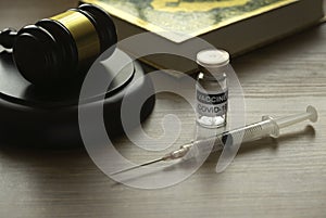 Sharia law and vaccination concept. Selective focus of bottle of covid-19 vaccine, gavel and syringe on wooden background photo