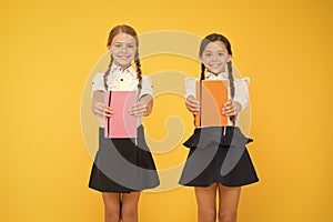 Sharing book love. Happy little girls holding books with colorful covers on yellow background. Cute small children