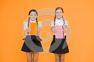 Sharing book love. Happy little girls holding books with colorful covers on yellow background. Cute small children