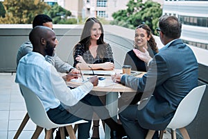 Sharing business insights around the table. a group of businesspeople having a meeting together on the balcony of an