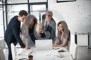 Sharing business insights as a team. a group of businesspeople using a laptop during a meeting in an office.