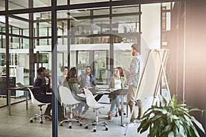 Sharing his feedback with the team. a businessman giving a presentation to his coworkers in a modern office.