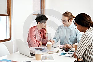Sharing his point of view. a diverse group of businesspeople sitting together and reading paperwork during a meeting in