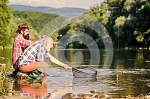 Sharing his secrets. Friends spend nice time at riverside. Beautiful evening riverside. Experienced fisherman show tips