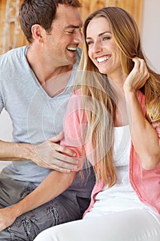 Sharing an intimate moment. A happy young couple sitting on the couch embracing lovingly.