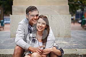 Sharing an intimate moment. A happy young couple sitting outside having an intimate moment.