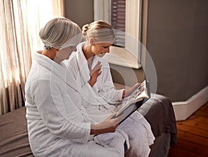 Sharing memories of a happy marriage. Grandmother and granddaughter flipping through a photo album.