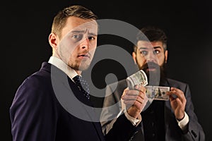 Sharing of profits concept. Meeting of reputable businessmen, black background. Man on serious face hold roll made out photo
