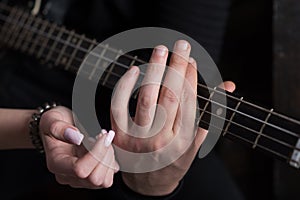 Sharing the rhythm of their life. Male and female hands play the electric guitar. Couple in love play duets. Couple of