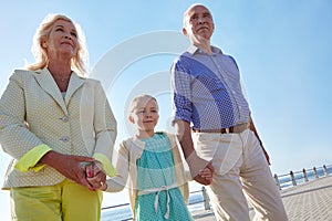 Sharing a sunny day together. grandparents walking hand in hand with their granddaughter on a promanade.