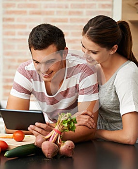 Sharing their recipes online. an attractive young couple using their tablet in the kitchen.