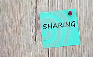 SHARING - word written on a green sheet for notes, which is pinned to a light wooden board