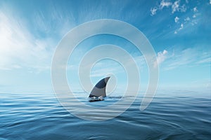 Shark fin on surface of ocean agains blue cloudy sky