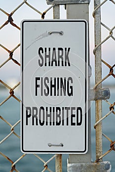 Shark Fishing Prohibited sign board at a pier with ocean view in Destin Florida