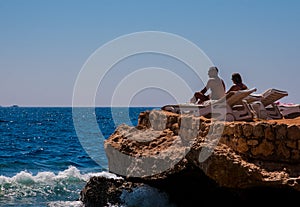 SHARM EL SHEIKH, EGYPT - JULY 9, 2009. Rear view of a romantic couple sitting on the sun loungers enjoying sea