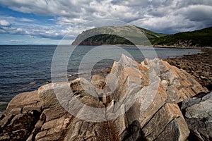 The sharp and angular rocks on the shore of the bay.