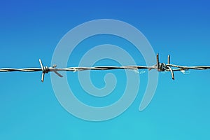 Sharp barbed wire against blue sky, containment and imprisonment concept photo
