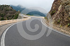 Sharp bends of winding mountain road and white clouds ahead. Rural Park Anaga in cloudy weather, Tenerife, Canary Islands, Spain