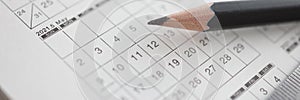 Sharp black pencil lying on calendar closeup