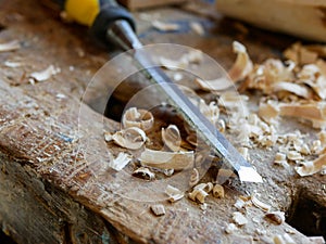 Sharp chisel, wood chips on old oak workbench, shallow depth of field