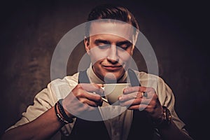 Sharp dressed man wearing waistcoat with a cup of coffee