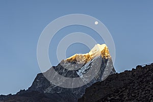 Sharp Himalayan mountain peak covered in snow with the moon in the background at sunrise  Everest Base Camp trek  Nepal