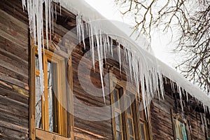 Sharp icicles hang on the edge of the roof, winter or spring.